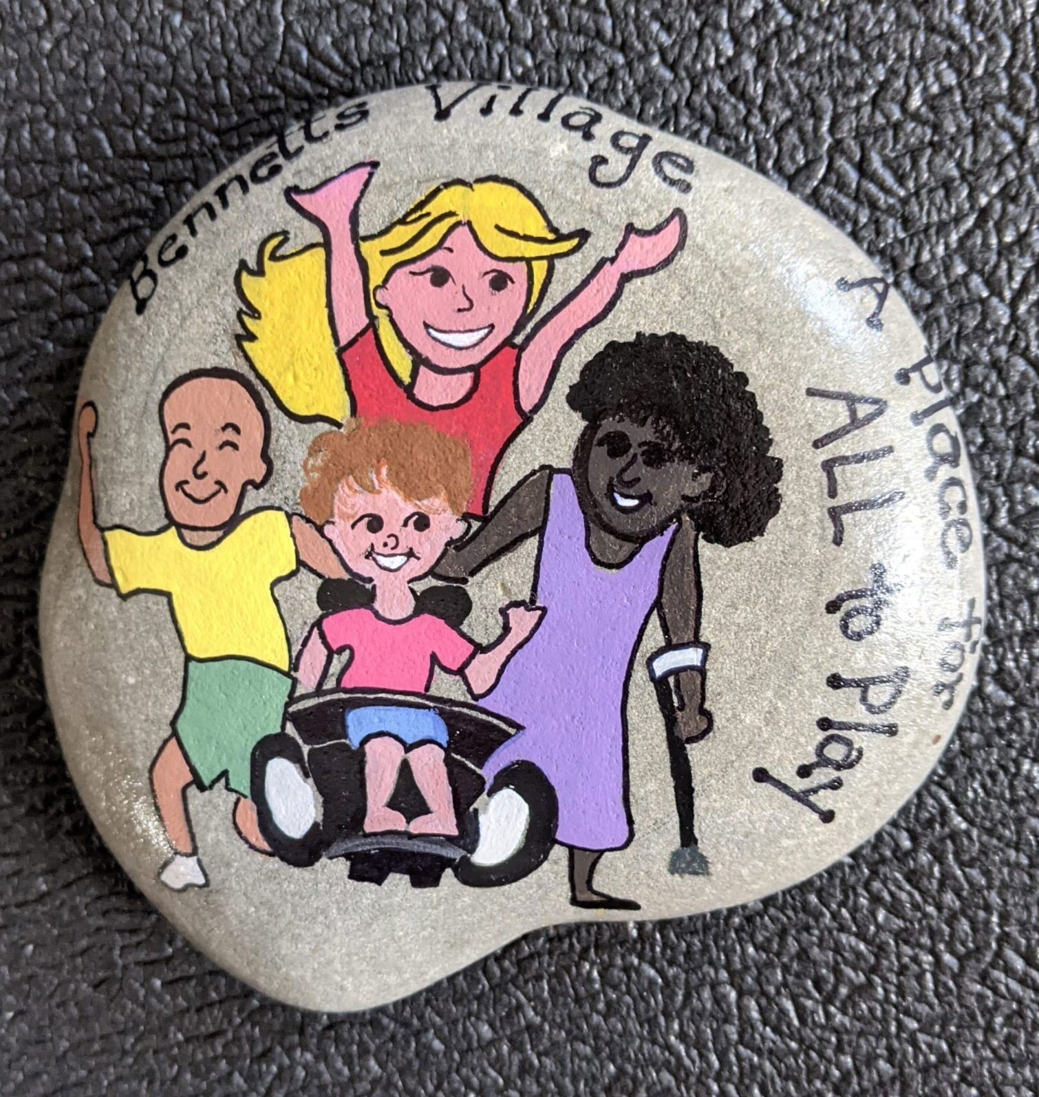 A rock painted by Gail Fehlner, Bennett’s Adaptive P.E. teacher. The rock features a painting of Bennett and friends.
