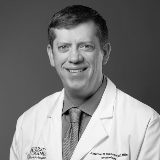 A smiling man wearing a white doctor's coat